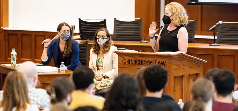 Woman wearing a mask being sworn in at a Umich lecturn