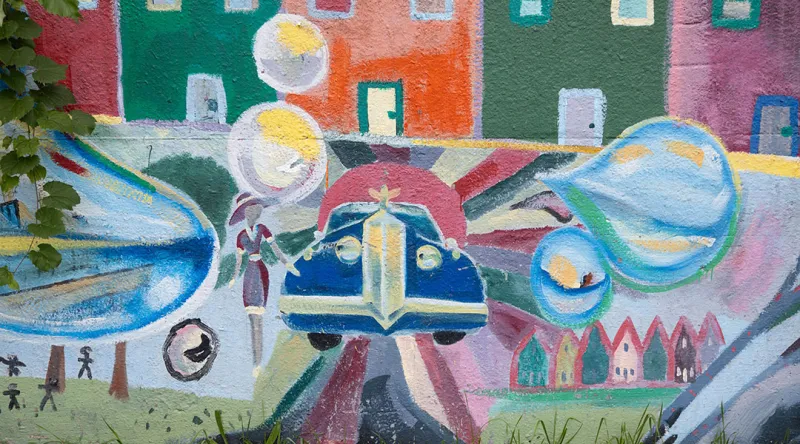 Mural of a car surrounded by buildings.