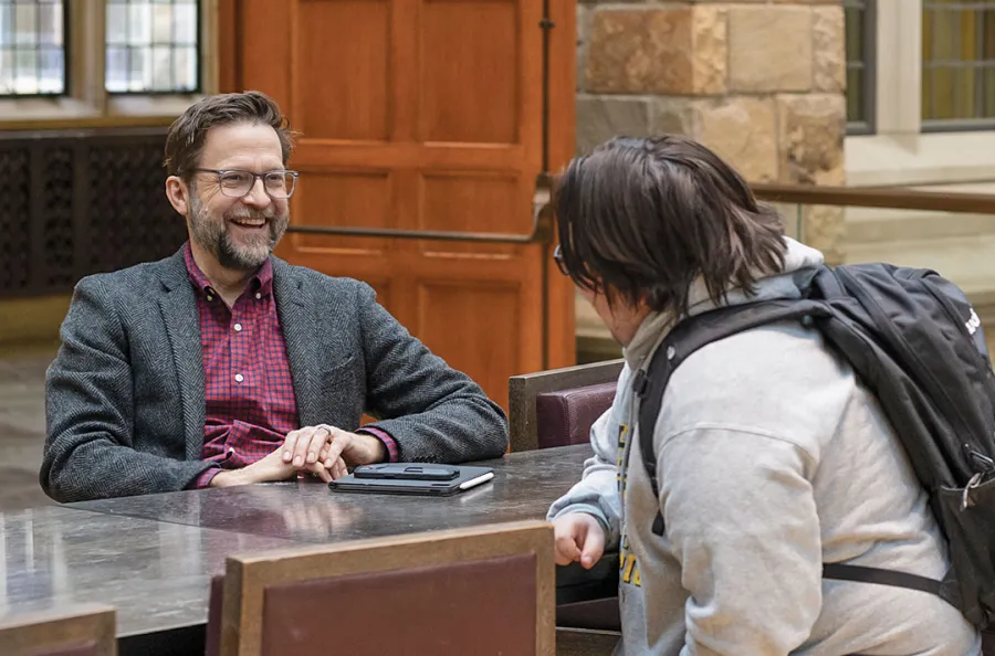 Intermin Dean Kyle Logue speaking with a student in the upper commons of Hutchins Hall.