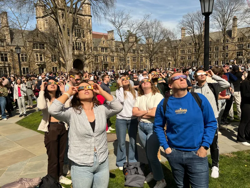 Hundreds of onlookers donning special glasses gather in the Law Quad to stare up at the solar eclipse.