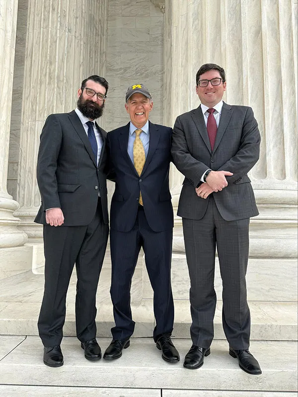 A portrait of Jonathan Tietz, ’19, Michael Huston, ’11, and Richard Friedman on the steps of the Supreme Court Building.