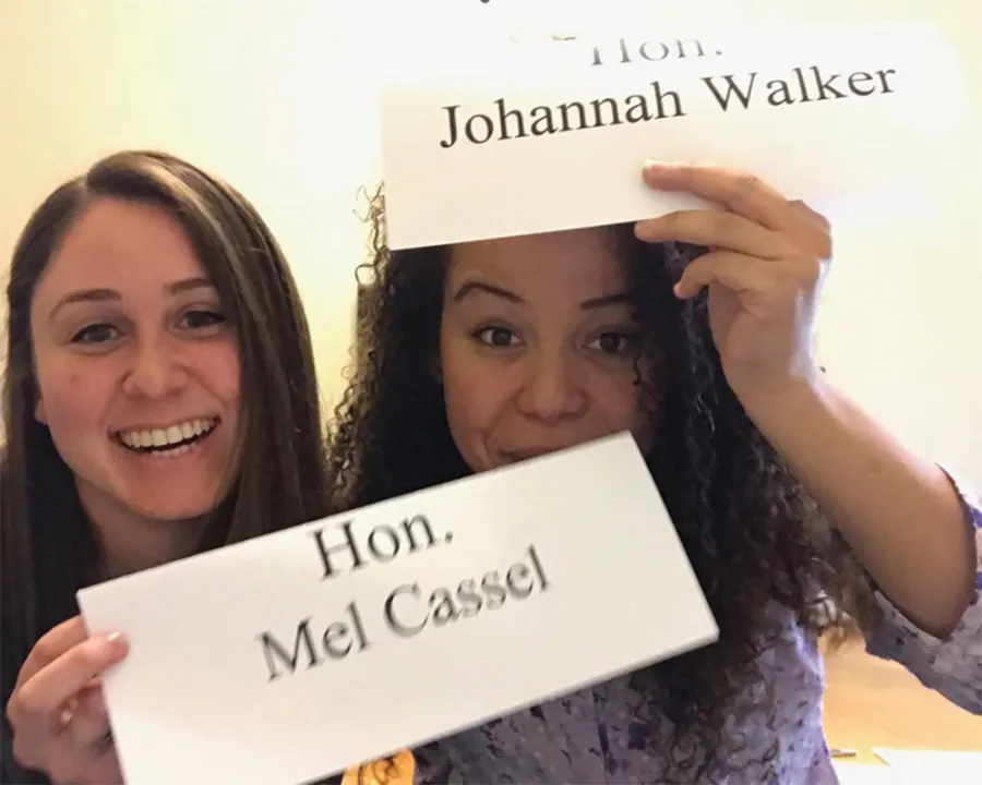 Two women hold signs with their names on them.
