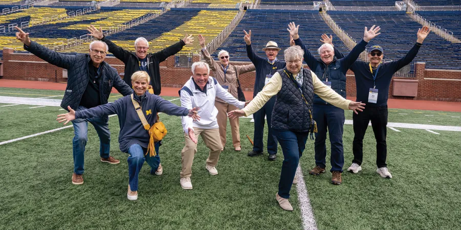 A group of Michigan Law Alumni Cheer on the Michigan Stadium field.