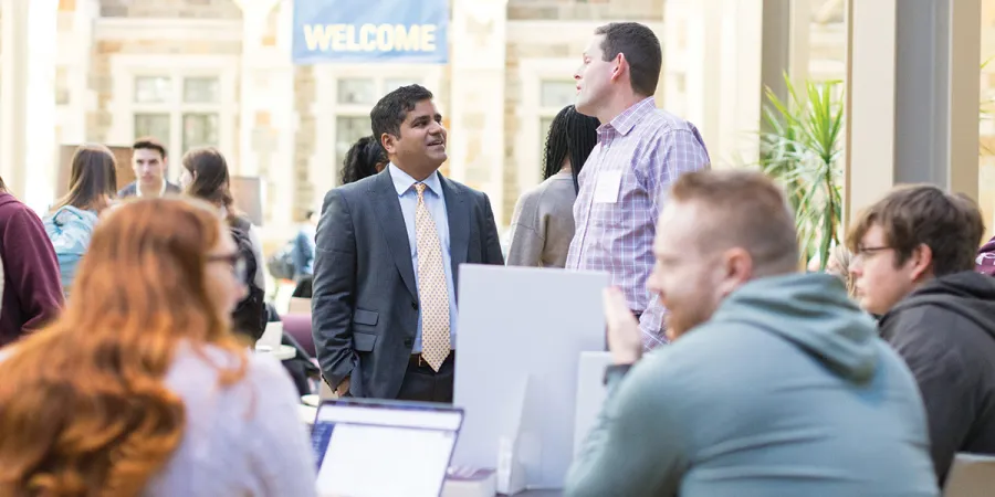 Dean Neel Sukhatme talking with Professor Matthew Andres in the upper commons.