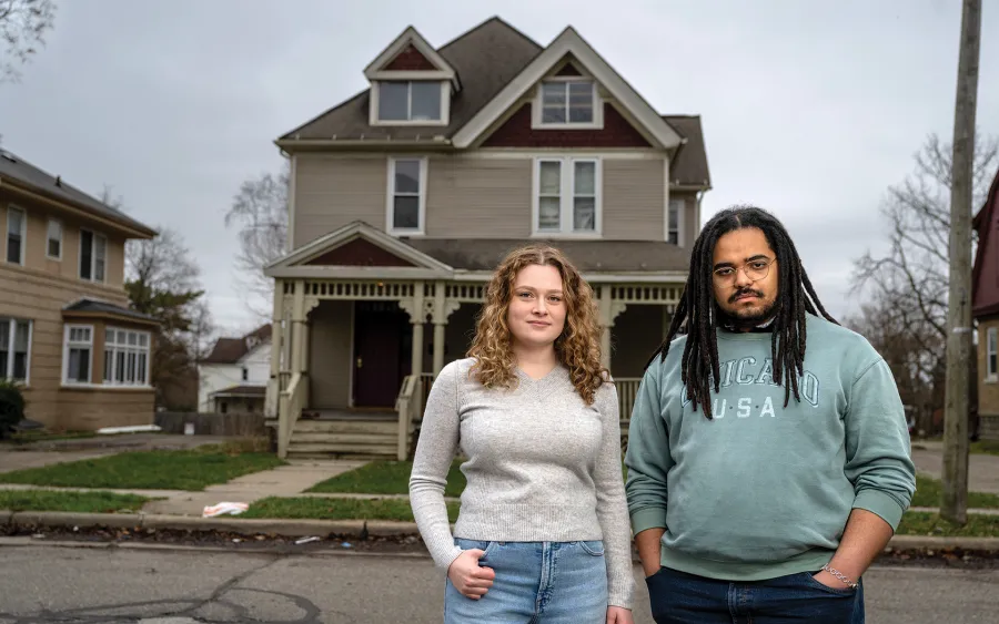 Abby Flynn and King Deas stand outside a rundown house.