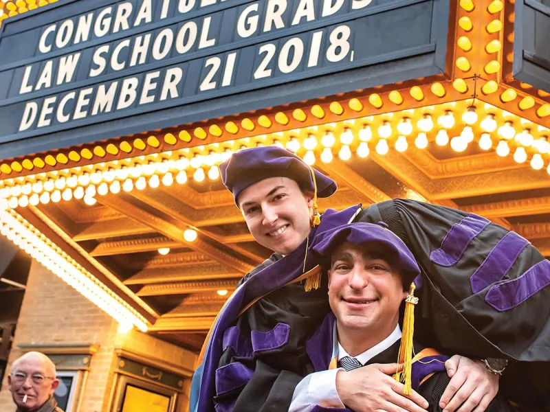 2 people standing outside of the Michigan theater after graduating