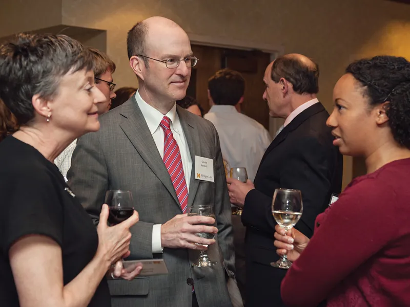 To alumni talking to an award recipient at a law school event