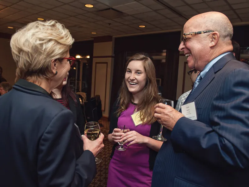 Two alumni talking to a law student at a law school event