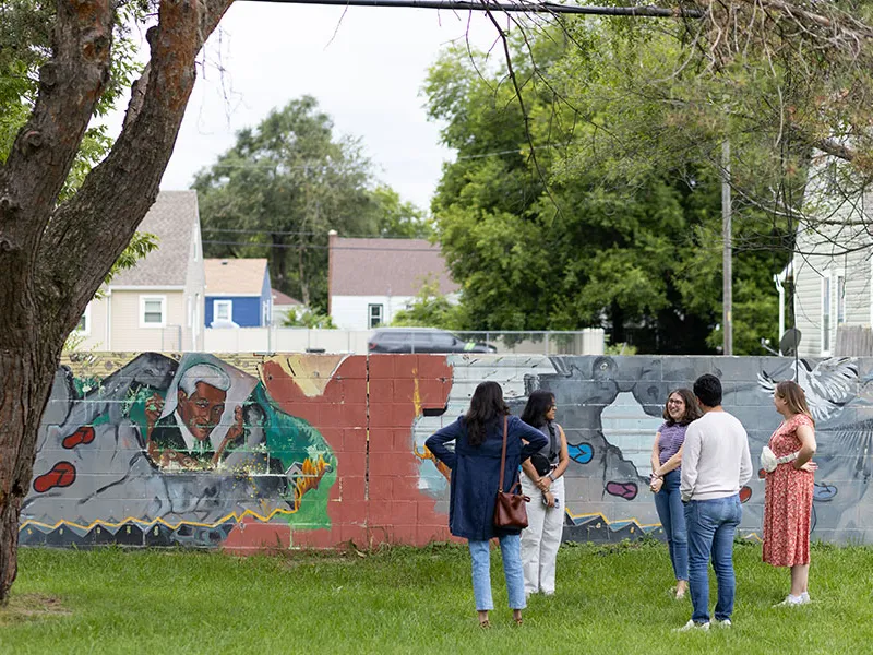 A group of students talking in front of a wall.