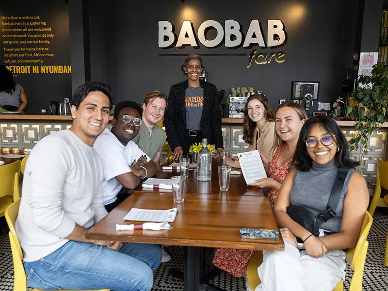 A group of students sitting at a table smiling.