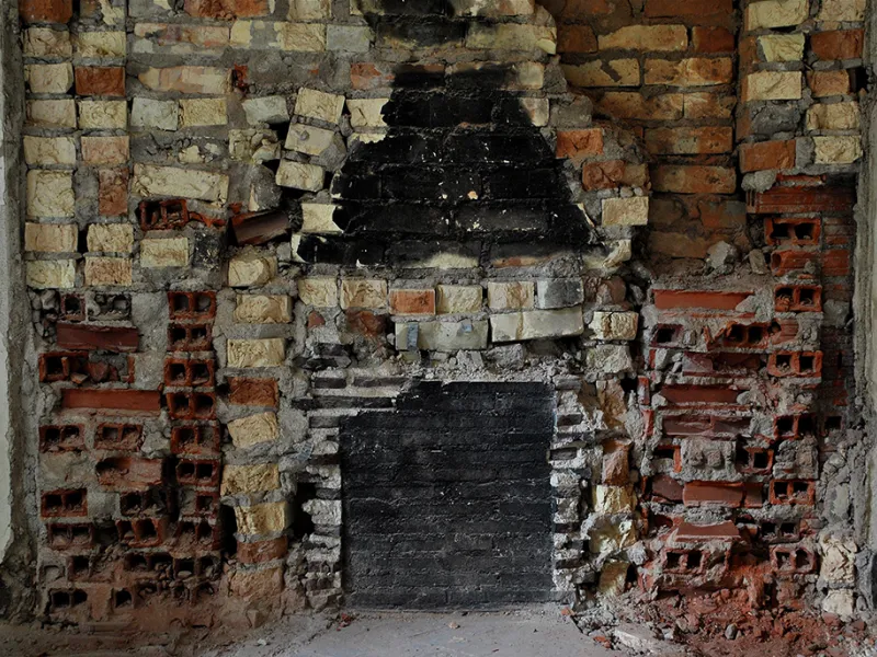 A brick wall shows the space where a fireplace was removed.