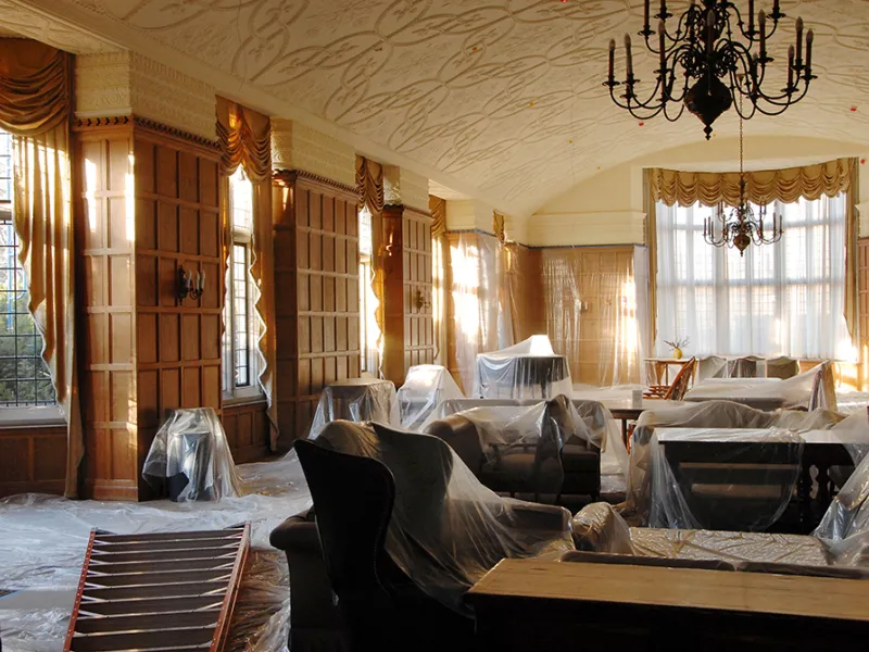 Plastic sheeting covers furniture in a wood paneled room of the Lawyers Club.