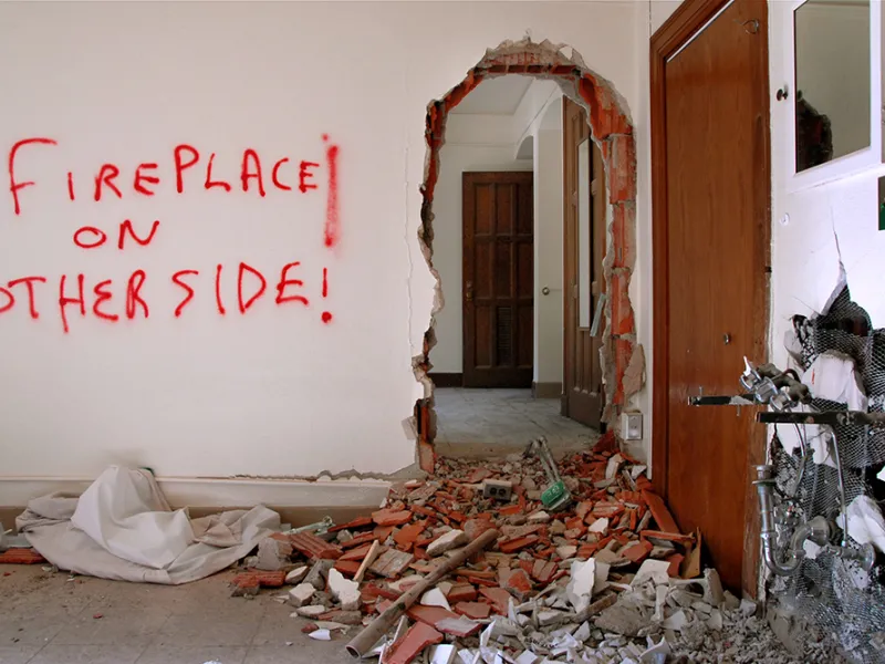 "Fireplace on other side!" is spray-painted on an interior wall of the Lawyers Club. Next to it, a doorway-size hole has been hammered out in the brick.