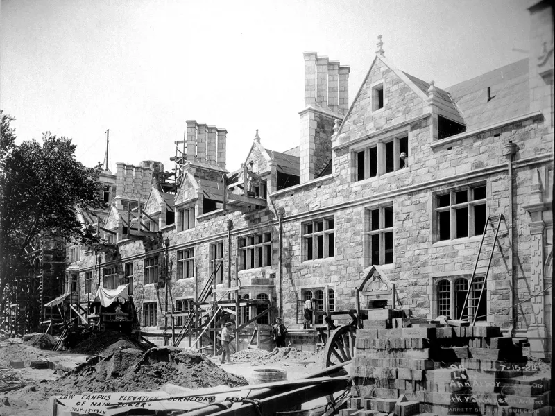 A stone building is under construction with equipment scattered in front of it.