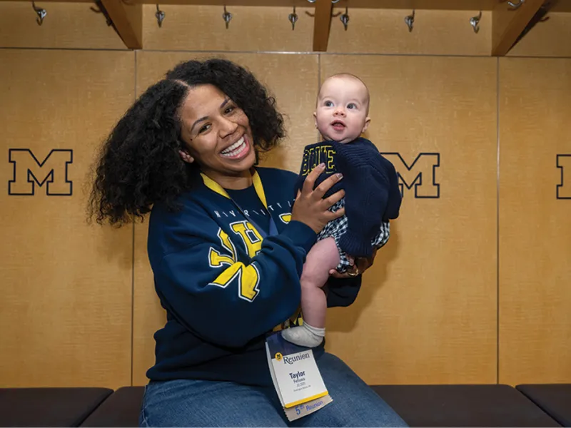 A Michigan Law alumni and their child in the Michigan Stadium locker room