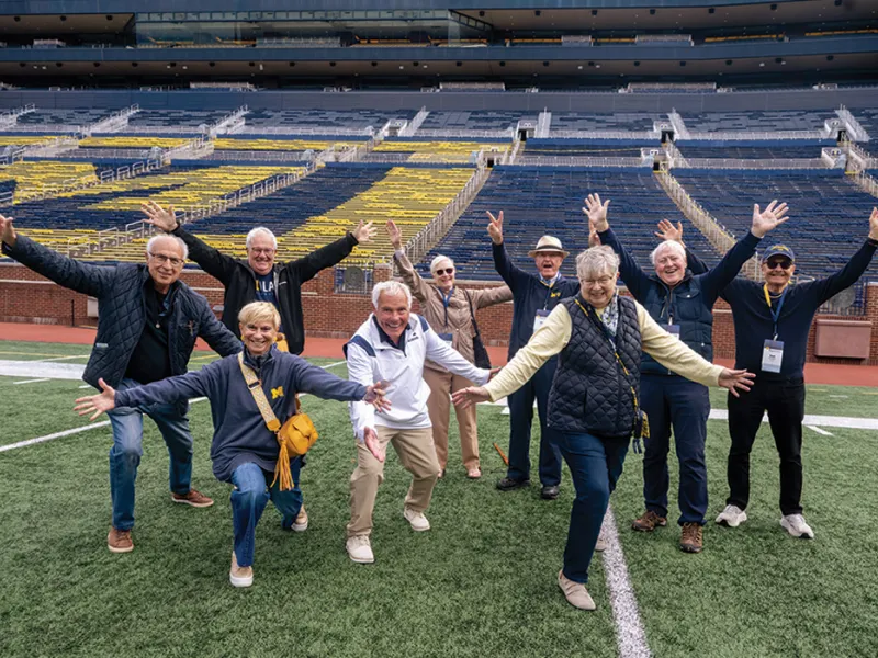 A group of Michigan Law alumni cheer on the Michigan Stadium field