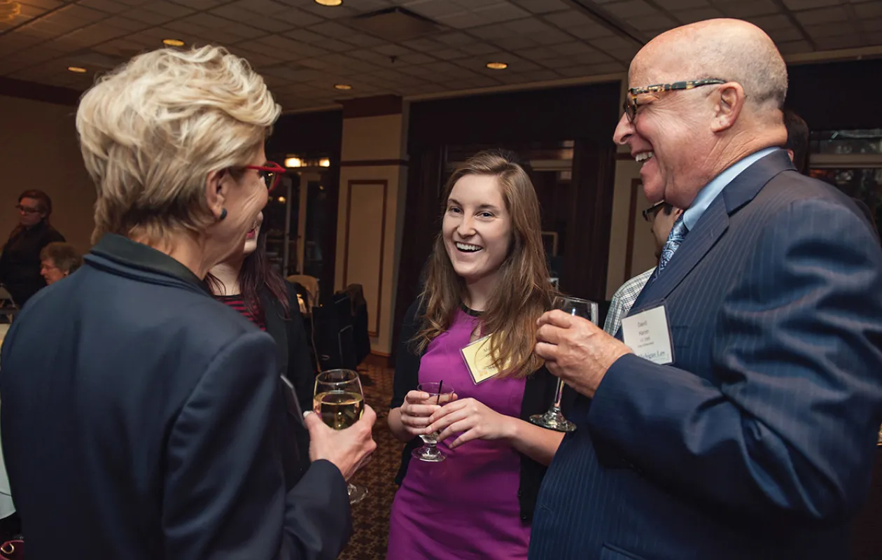 Two alumni talking to a law student at a law school event