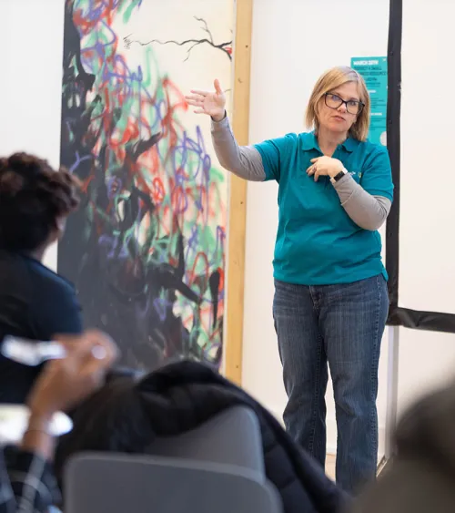 A portrait of Christie Baer, DNEP’s managing director speaking in front of a group.