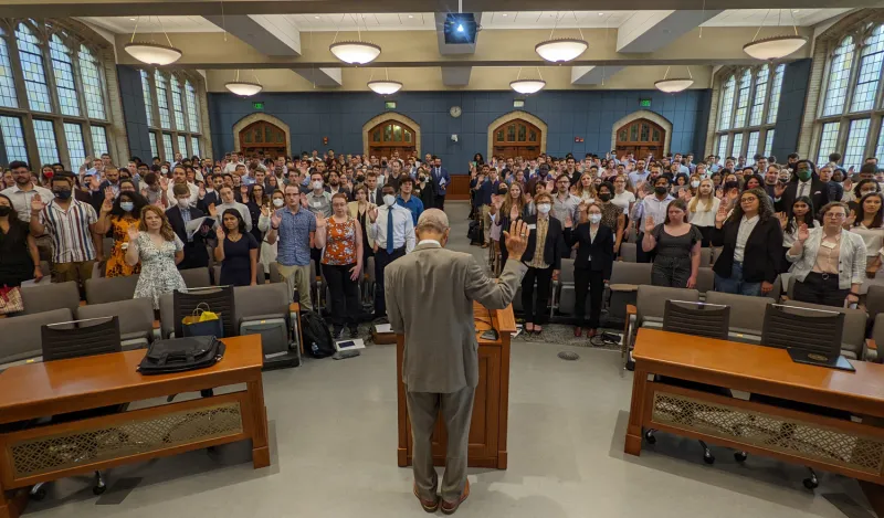 the Hon. Gershwin Drain, ’72 stood at lectern with hand raised leading students in a swearing in ceremony