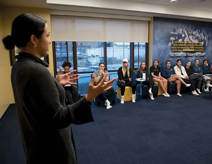 Student-attorney Emily Gaudiani, pictured above speaking with the U-M softball team, says looking at NIL through an equity lens presents several questions, including how to support female student-athletes.