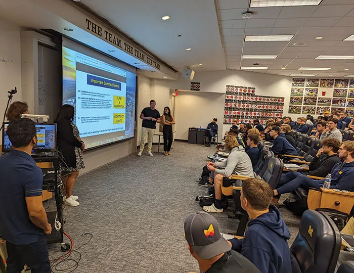 Andrew  Watson, ’23, and Emily Gaudiani, a dual JD/MBA student, make  their presentation to the football team.