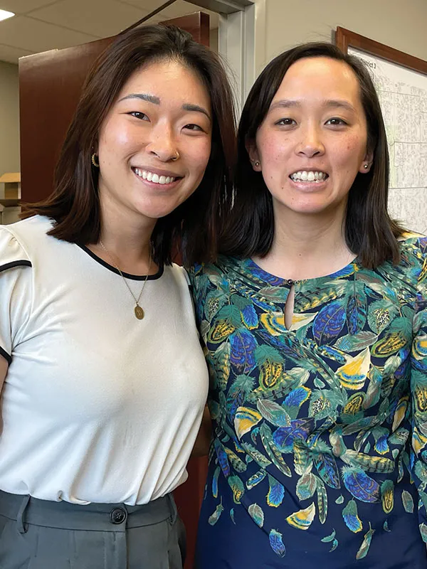 Two people standing next to each other smile for a photograph.