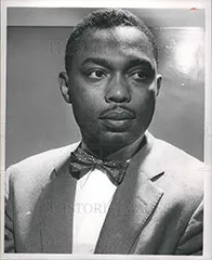 A man in a suit and bowtie looks to the side.