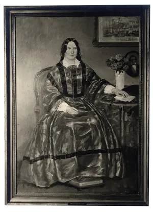 A woman sits at a table in a long dress.