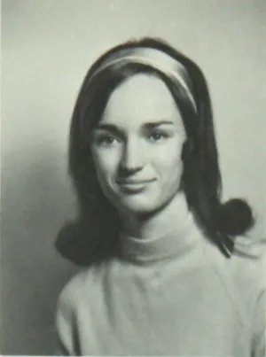 A woman with shoulder length hair an da headband smiles for her law school photo.