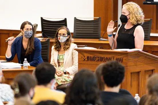 Woman wearing a mask being sworn in at a Umich lecturn