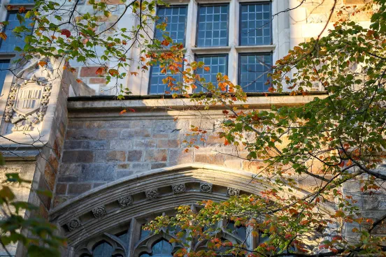 Beautiful image of the University of Michigan law school's architecture. There are trees starting to bloom in the foreground.