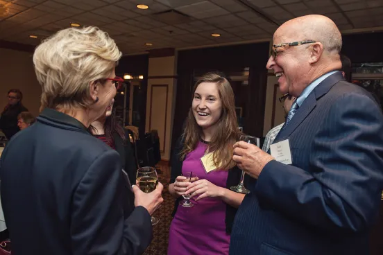 Two alumni talking to a law student at a law school event