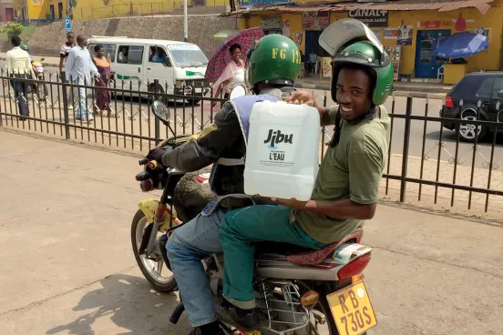 Two of Jibu's local entrepreneurs holding a container of water with Jibu logo
