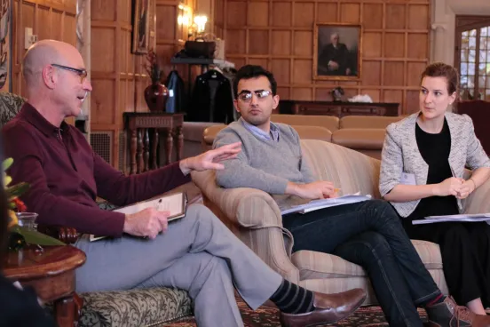 Three people are talking sitting on sofas at the refugee conference