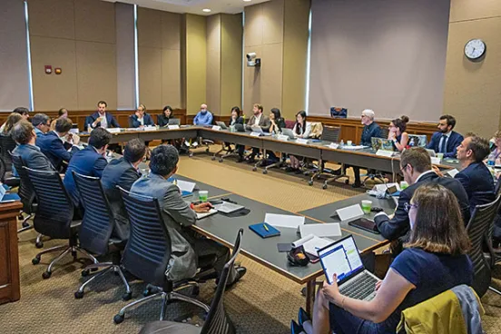 Conference participants sitting around a large table.