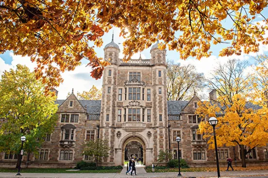A student walks in front of the Lawyers Club in the warm autumn light.