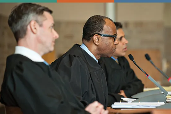 Judges at Michigan Law Three judges in black robes seated at a court bench, engaged in discussion, with microphones and papers in front of them.