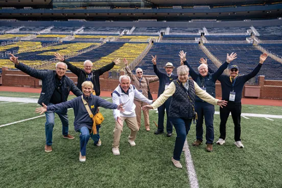 A group of Michigan Law Alumni Cheer on the Michigan Stadium field.