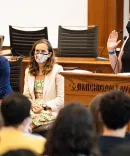 Woman wearing a mask being sworn in at a Umich lecturn