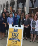 A group of people from the Michigan Law School Tax Clinic smiling and standing together feeling proud of the work they are accomplishing.  