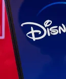 An iPhone shows the Disney Plus app in front of the Marvel logo.