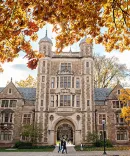 A student walks in front of the Lawyers Club in the warm autumn light.