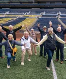 A group of Michigan Law Alumni Cheer on the Michigan Stadium field.